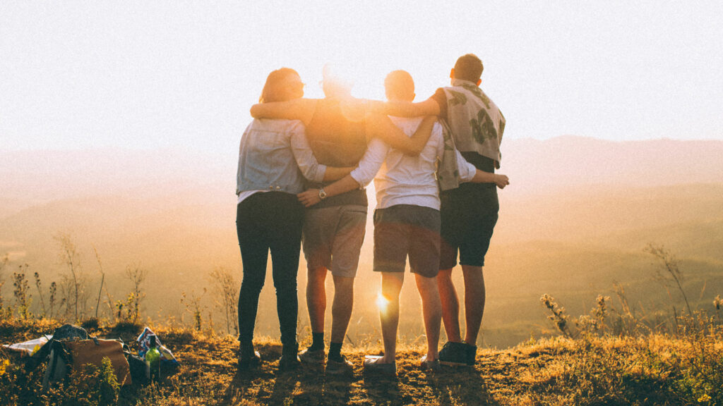 Quatre jeunes de dos regardant le coucher de soleil