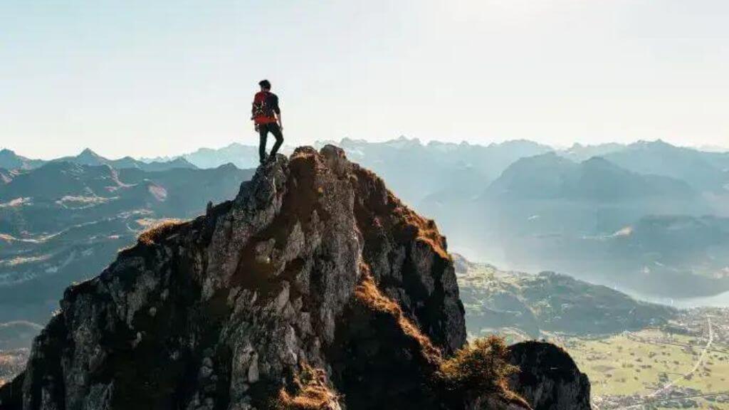 humain sur le haut d'une montagne regardant une chaîne de montagne à l'horizon